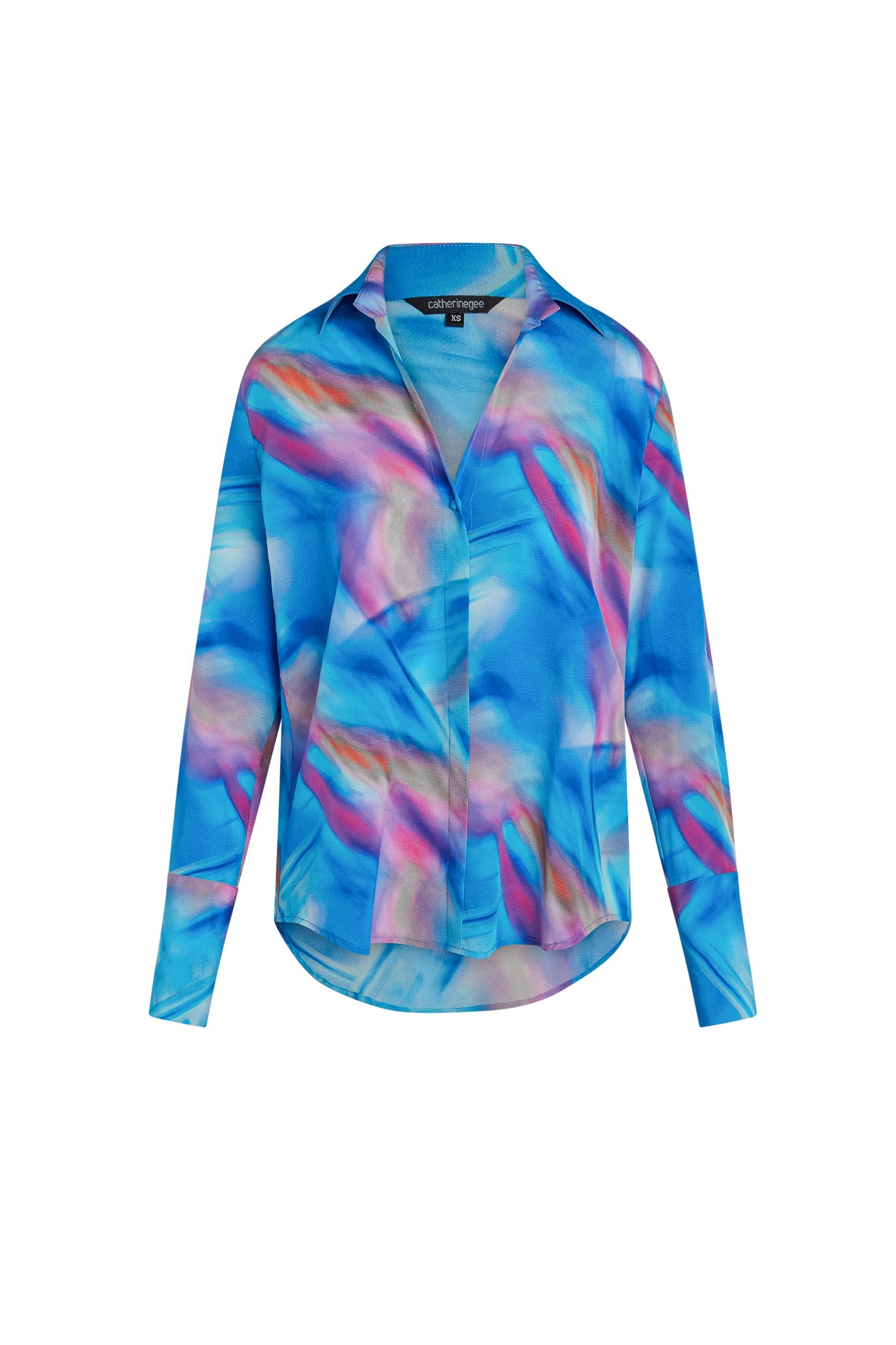 Catherine Gee Daria French Cuff Silk Blue Prism blouse features a vibrant abstract design with shades of blue, pink, and purple. It has a classic collar, long sleeves with French cuffs, and a button-down front. The fabric appears lightweight and flowy, giving it an elegant and stylish look.