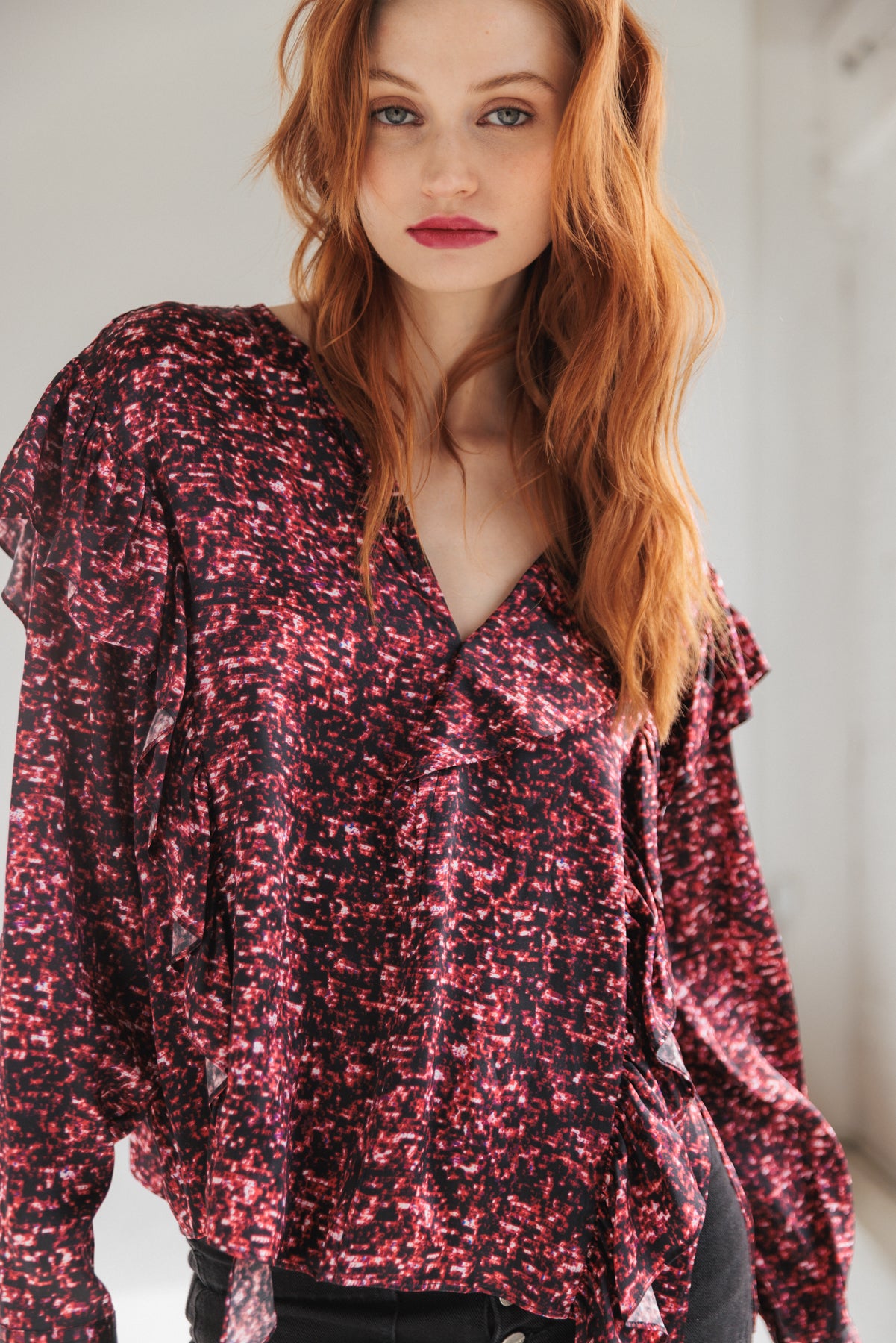 A woman is wearing a Catherine Gee Bella Blouse - Red Sequin features a V-neckline and long sleeves with a loose, flowing fit.