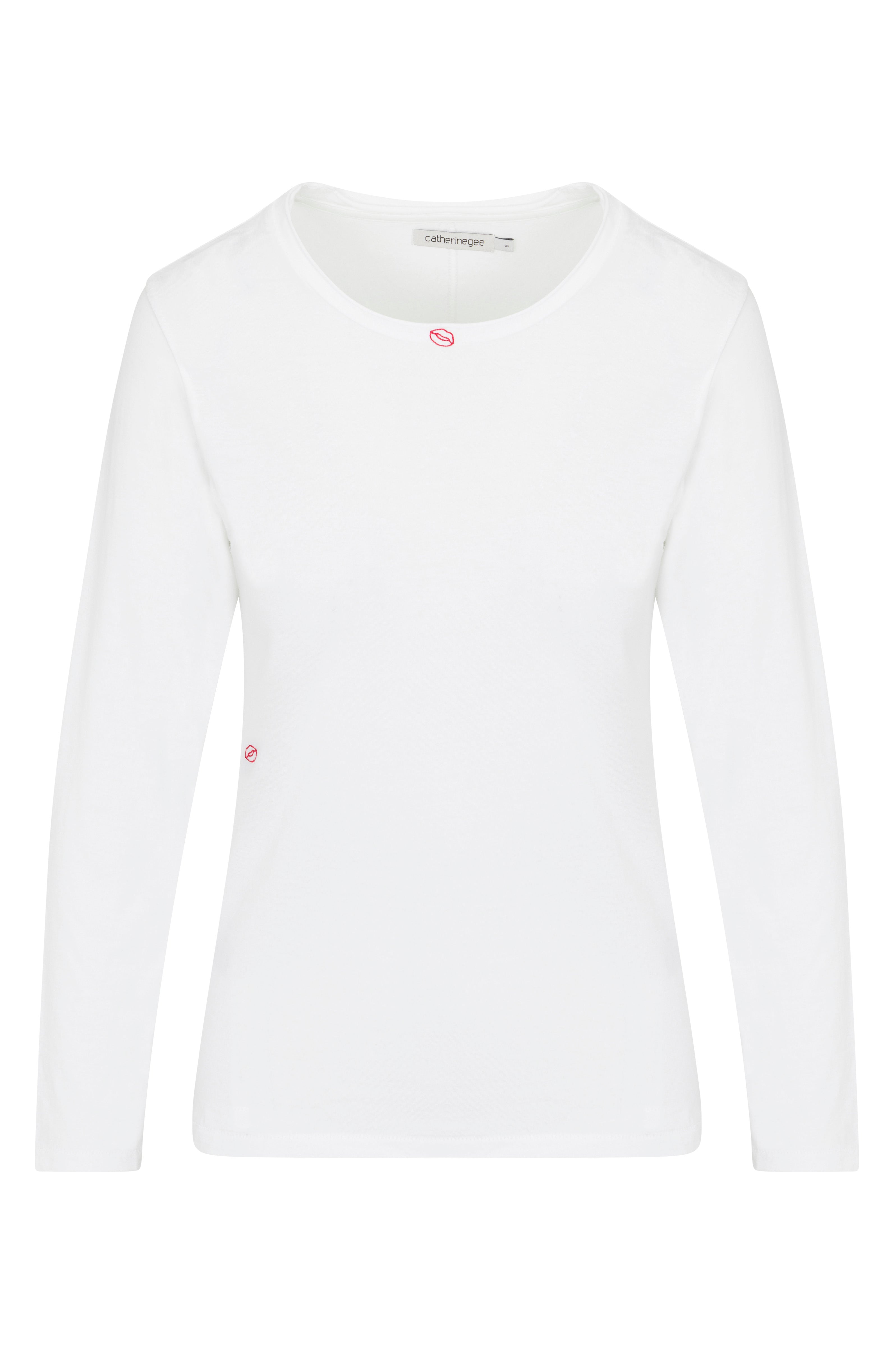 Catherine Gee Embroidered Cotton Long Sleeve Bisou white t-shirt features long sleeves and a round neckline. The design includes small, subtle embroidered details, such as a small red "Bisou" (French for "kiss") near the neckline and another small red detail on the left side near the waist. It is made of soft, comfortable cotton, making it a perfect choice for casual, everyday wear.