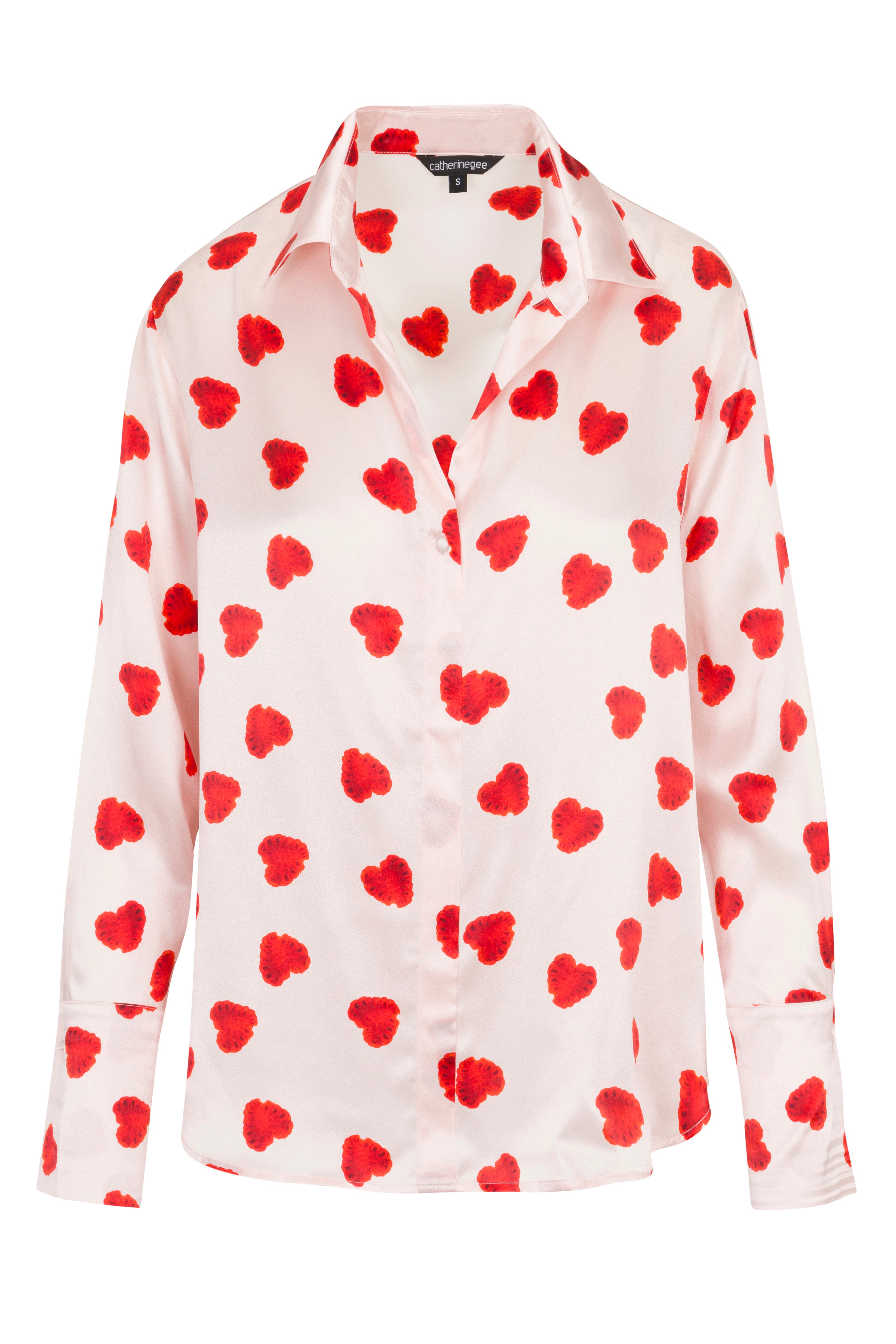 Catherine Gee Daria French Cuff Silk Raspberry Heart blouse features a white base color with a red raspberry-colored heart pattern, a classic collar, a button-down front, and long sleeves with French cuffs. The silk material gives it a smooth and elegant appearance, making it a stylish and eye-catching piece perfect for adding a touch of whimsy to any wardrobe.