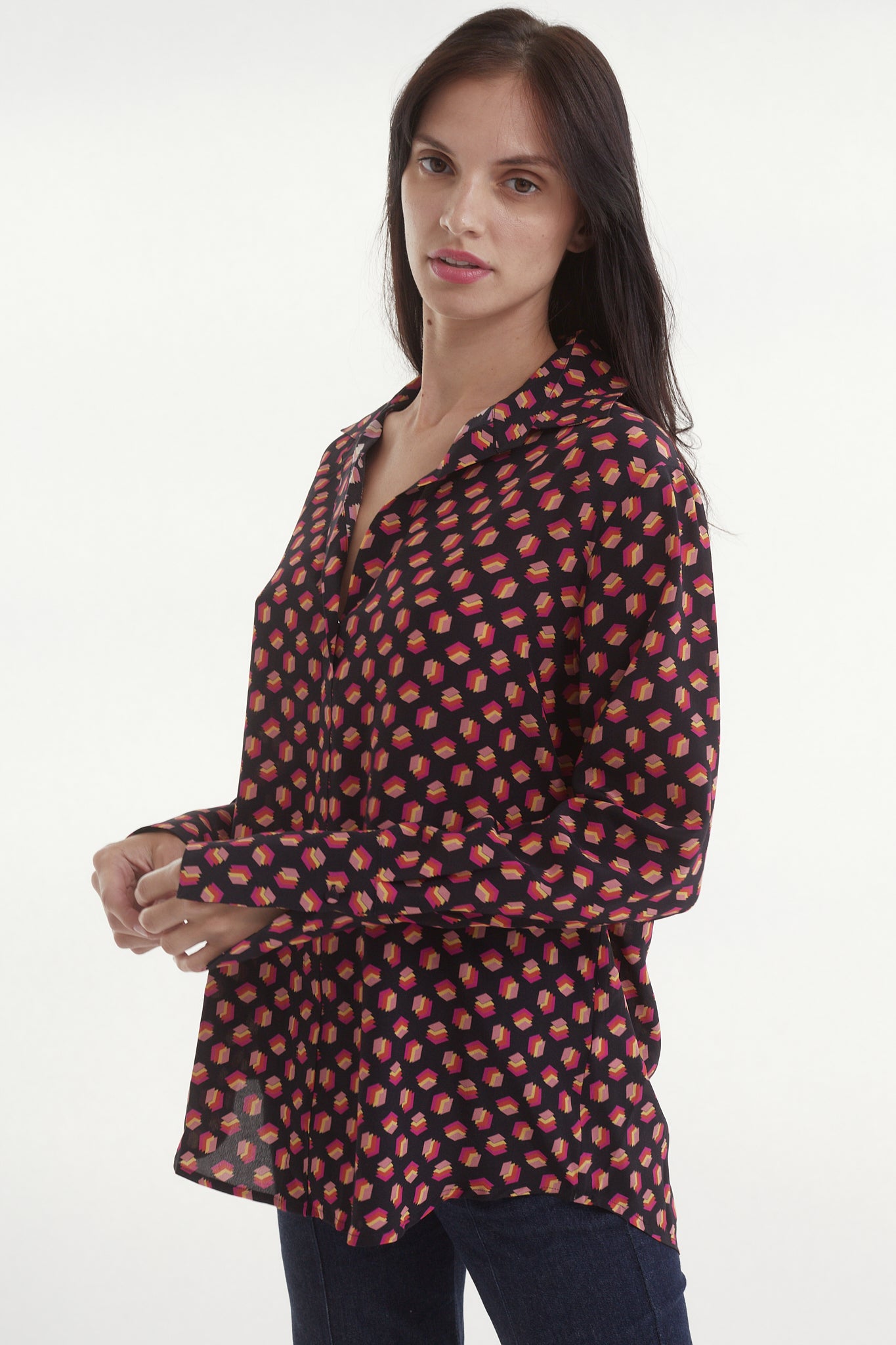 A Catherine Gee Daria French Cuff Silk-Libros Print blouse features a dark background with a pattern of small, red, book-like shapes. It has a relaxed fit, long sleeves with French cuffs, and a button-down front highlighting the blouse's design and fit.