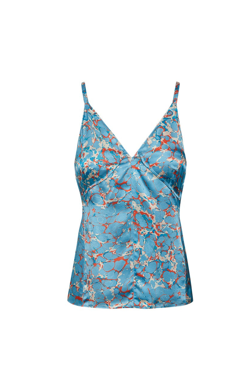 A blue Catherine Gee Catherine Corfu tank top with a marbled pattern in shades of red and white. The tank top has thin straps and a V-neckline. The fabric appears to be silky and smooth, giving it a luxurious look.
