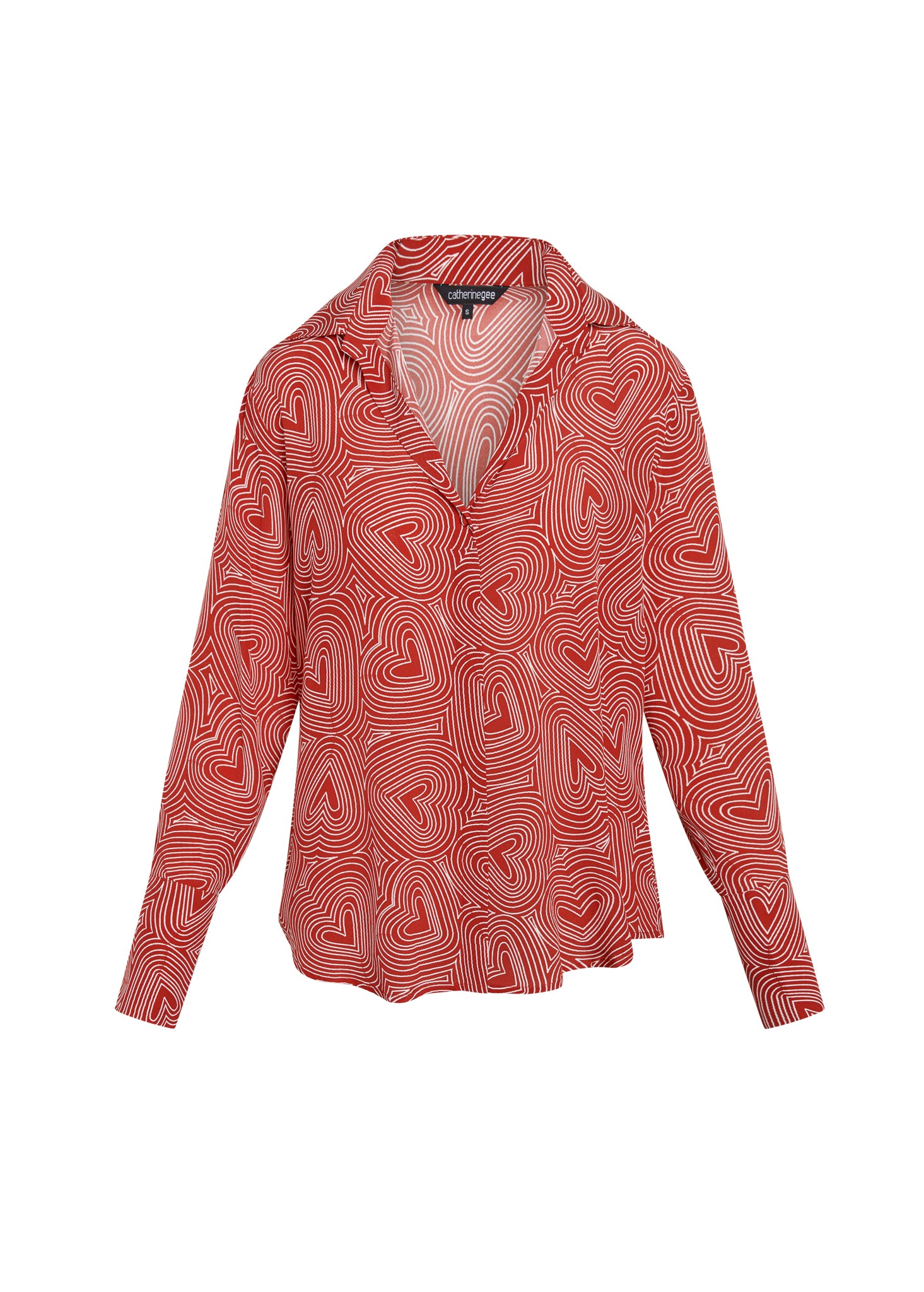Daria French Cuff Silk Blouse - Bowie Heart features a red silk blouse with a white heart pattern, V-neckline, long sleeves with French cuffs, and a relaxed fit. designed by Catherine Gee. The pattern consists of concentric hearts, creating a visually striking and elegant design.