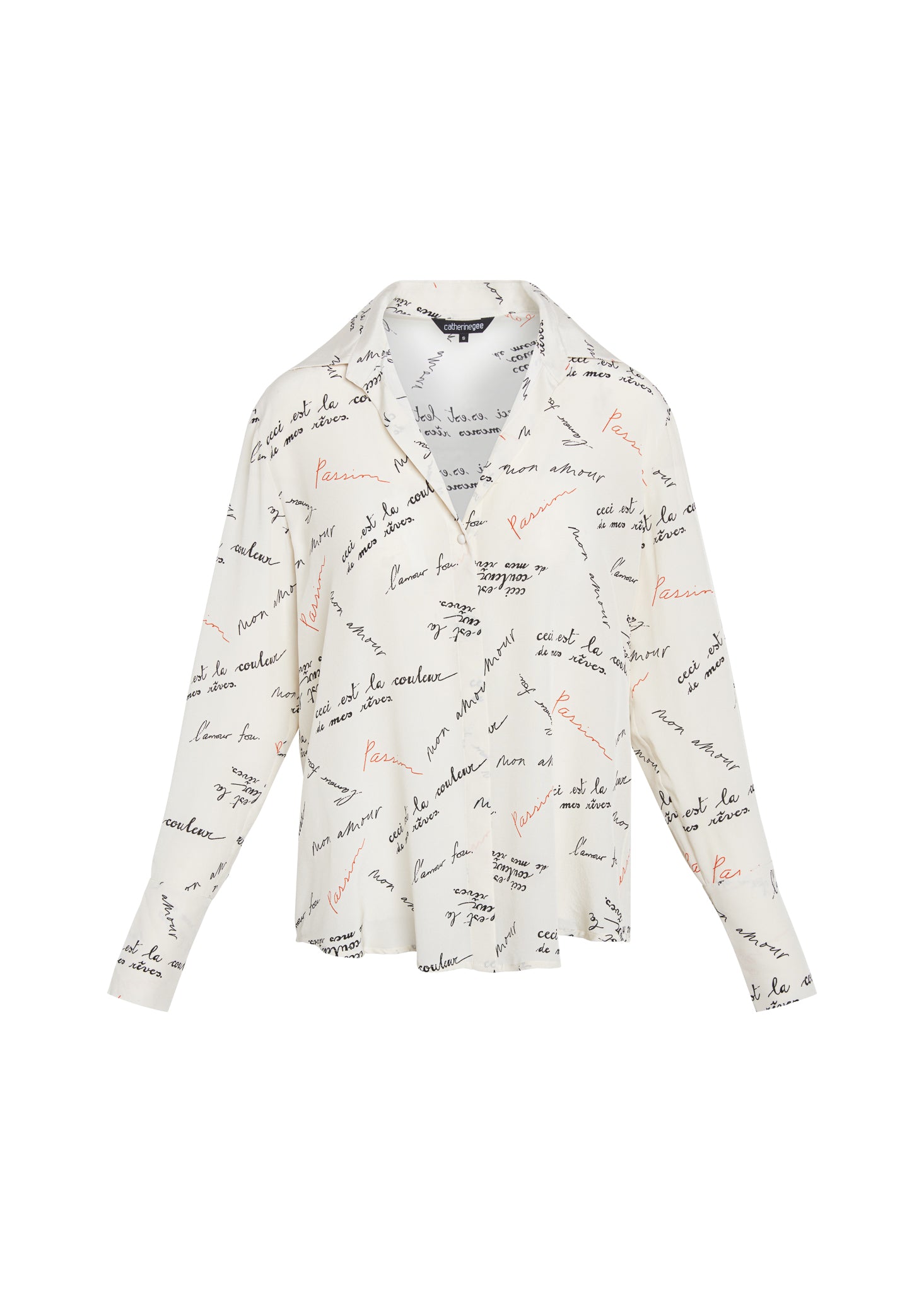 Catherine Gee Daria French Cuff Silk Passion Print blouse features a pattern of handwritten text in black and red ink on a white background that appears to be in French, adding a sophisticated and artistic touch to the garment. The blouse has a classic collar, long sleeves with French cuffs, and a relaxed fit with an overall design that is elegant and stylish, making it a versatile piece for various occasions.