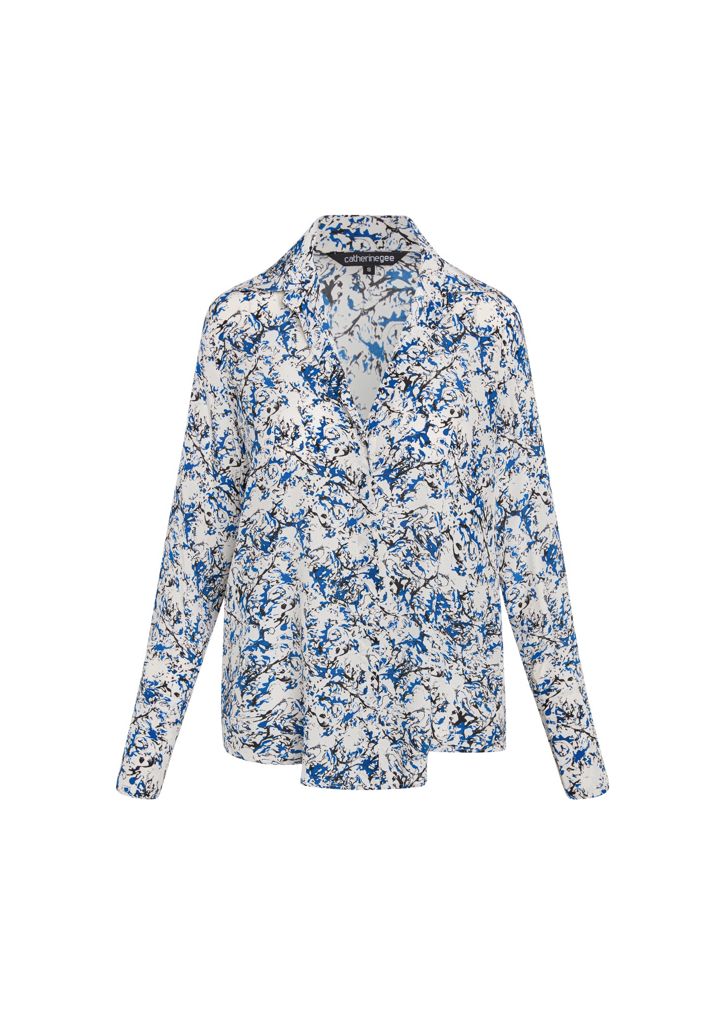Catherine Gee Daria French Cuff Silk Santorini blouse features a white base with an abstract blue and black splatter print. It has a classic collar, long sleeves with French cuffs, and a relaxed fit. The design is elegant and versatile, suitable for both casual and formal occasions. The silk material adds a luxurious touch, making it a stylish and comfortable choice.