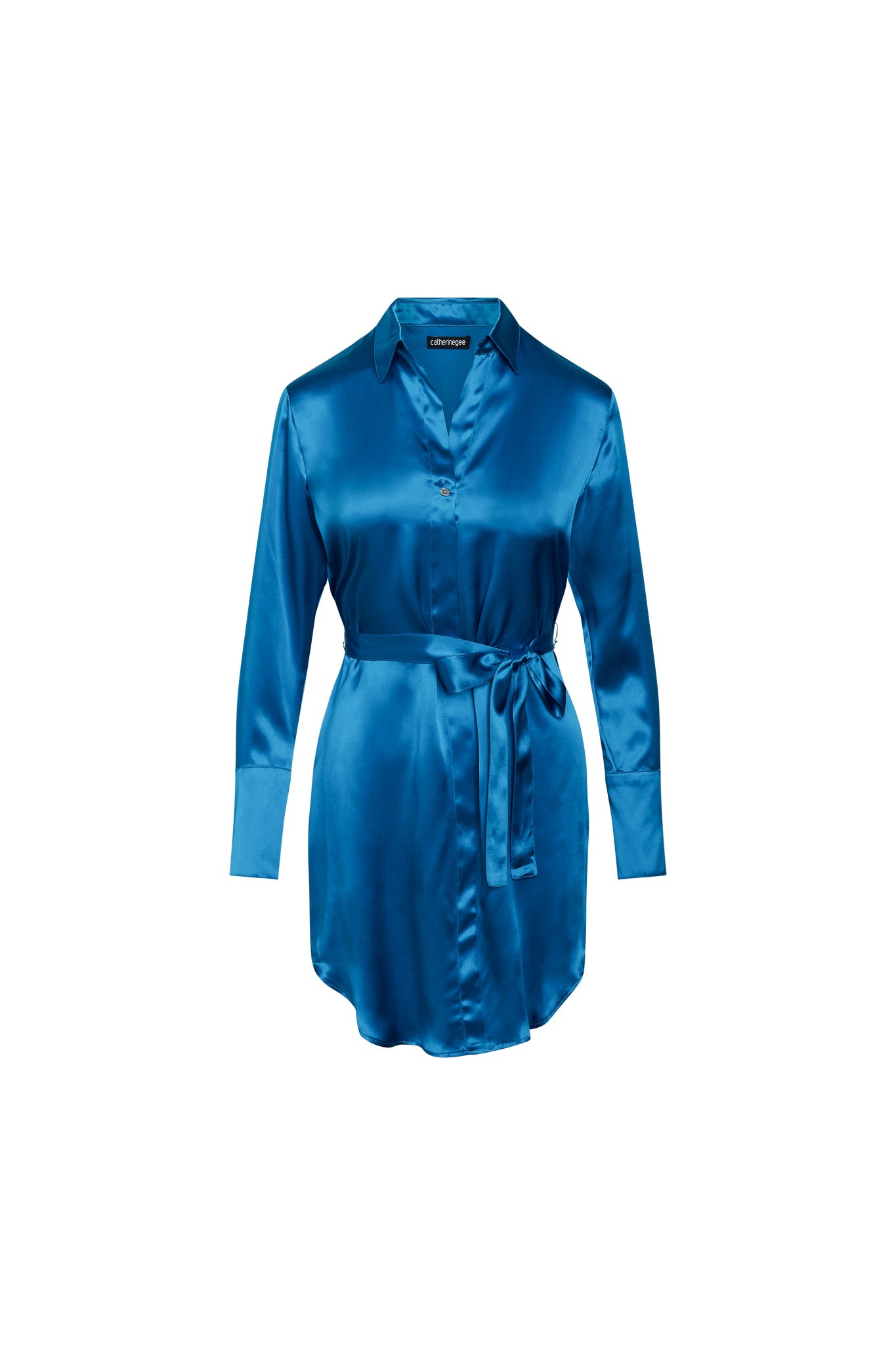 Catherine Gee Daria Silk Shirt Teal Dress. This elegant dress features a vibrant teal color with a classic shirt collar, long sleeves with buttoned cuffs, and a button-down front, including a self-tie belt at the waist, adding shape and definition to the silhouette. The smooth, shiny silk fabric gives the dress an elegant and luxurious look, perfect for various occasions.