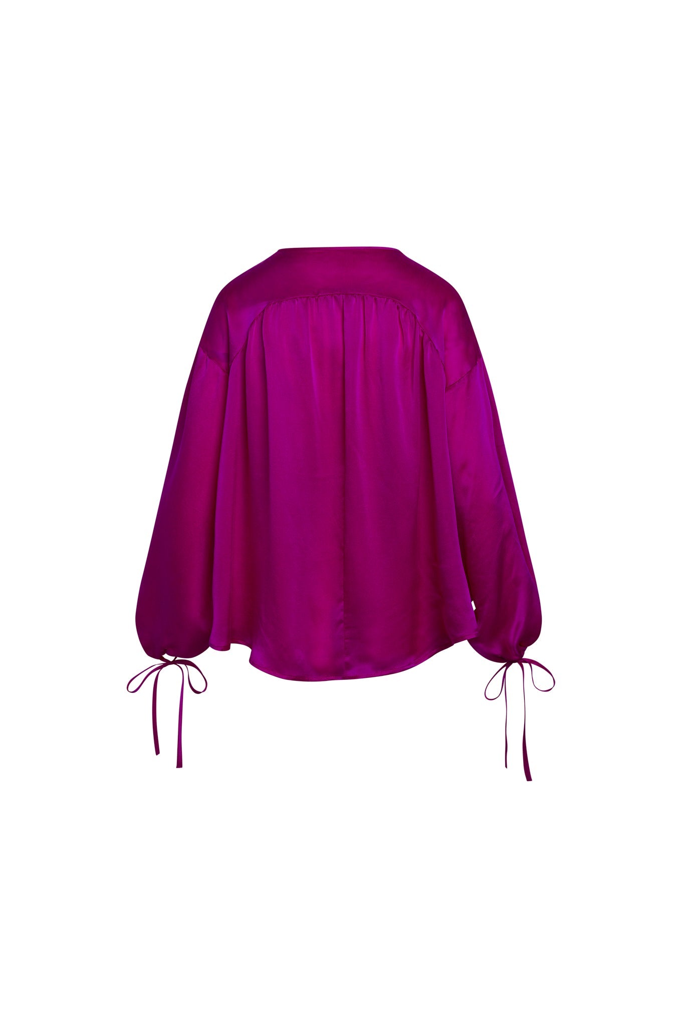 Back-view of a Catherine Gee Frances Hot Pink blouse is vibrant hot pink in color and features a loose, flowing design. It has long sleeves that gather at the wrists with ties, creating a billowy effect, and has a simple, elegant cut with a slightly rounded hemline. The fabric appears to be silky and smooth, giving it a luxurious look.