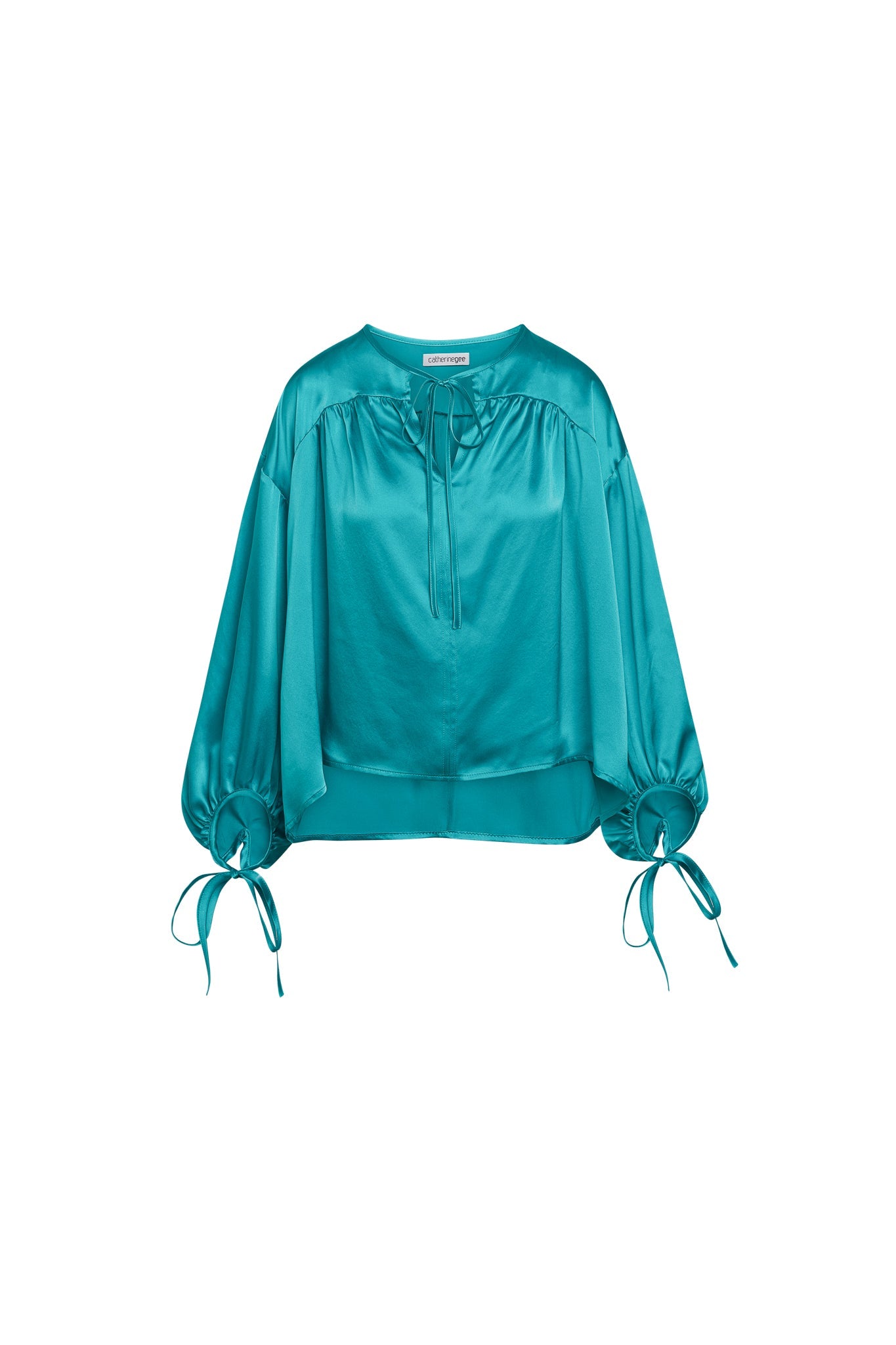 Catherine Gee Frances Van Gogh Green Blouse. This elegant blouse, made of shiny, silky fabric, is vibrant green. It features a loose, flowing fit with long sleeves gathered at the wrists and tied with matching fabric ribbons. The round neckline has a small V-cut and a tie closure, adding a delicate touch. The blouse's luxurious texture and unique color make it a standout piece, perfect for various occasions.