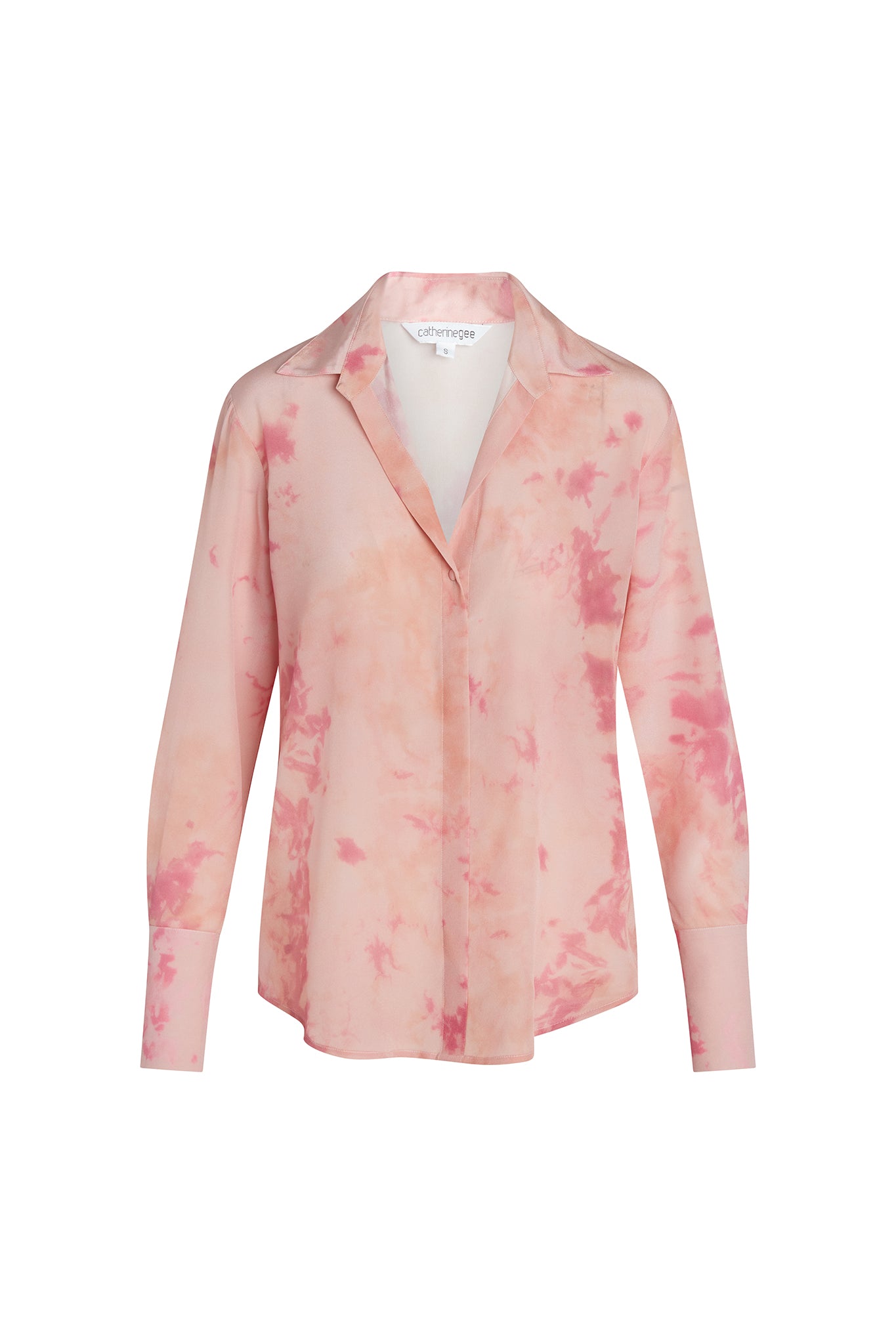 A Catherine Gee Daria French Cuff Silk Pink Ink blouse features an ink-like pattern in shades of pink. It has a classic collar, long sleeves with French cuffs, and a button-down front, and appears to be lightweight and silky, giving it a luxurious and elegant look. The design is both stylish and versatile, suitable for various occasions.