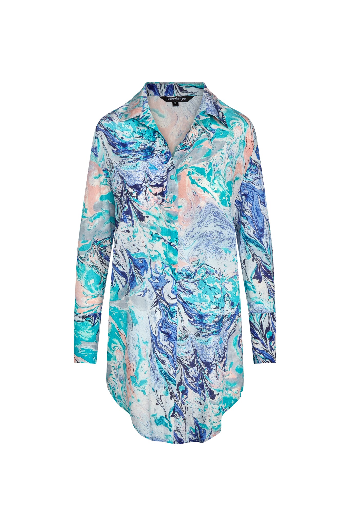Catherine Gee Daria Shirt Cool Swirl Dress features a vibrant, abstract swirl pattern in shades of blue, teal, and peach. It has a classic collar, long sleeves with French cuffs, and a button-down front. The design is elegant and eye-catching, making it a stylish choice for various occasions and the silk material adds a luxurious touch to the overall appearance.