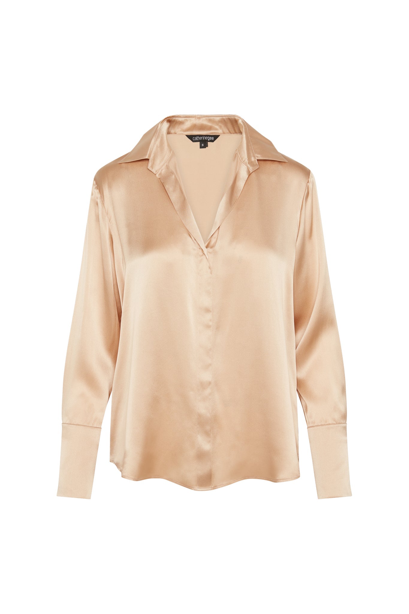 Catherine Gee Daria French Cuff Silk-Champagne blouse features a smooth, shiny silk fabric with a relaxed fit, a V-neckline, and a classic collar. The long sleeves end in French cuffs, adding a touch of elegance to the overall design.