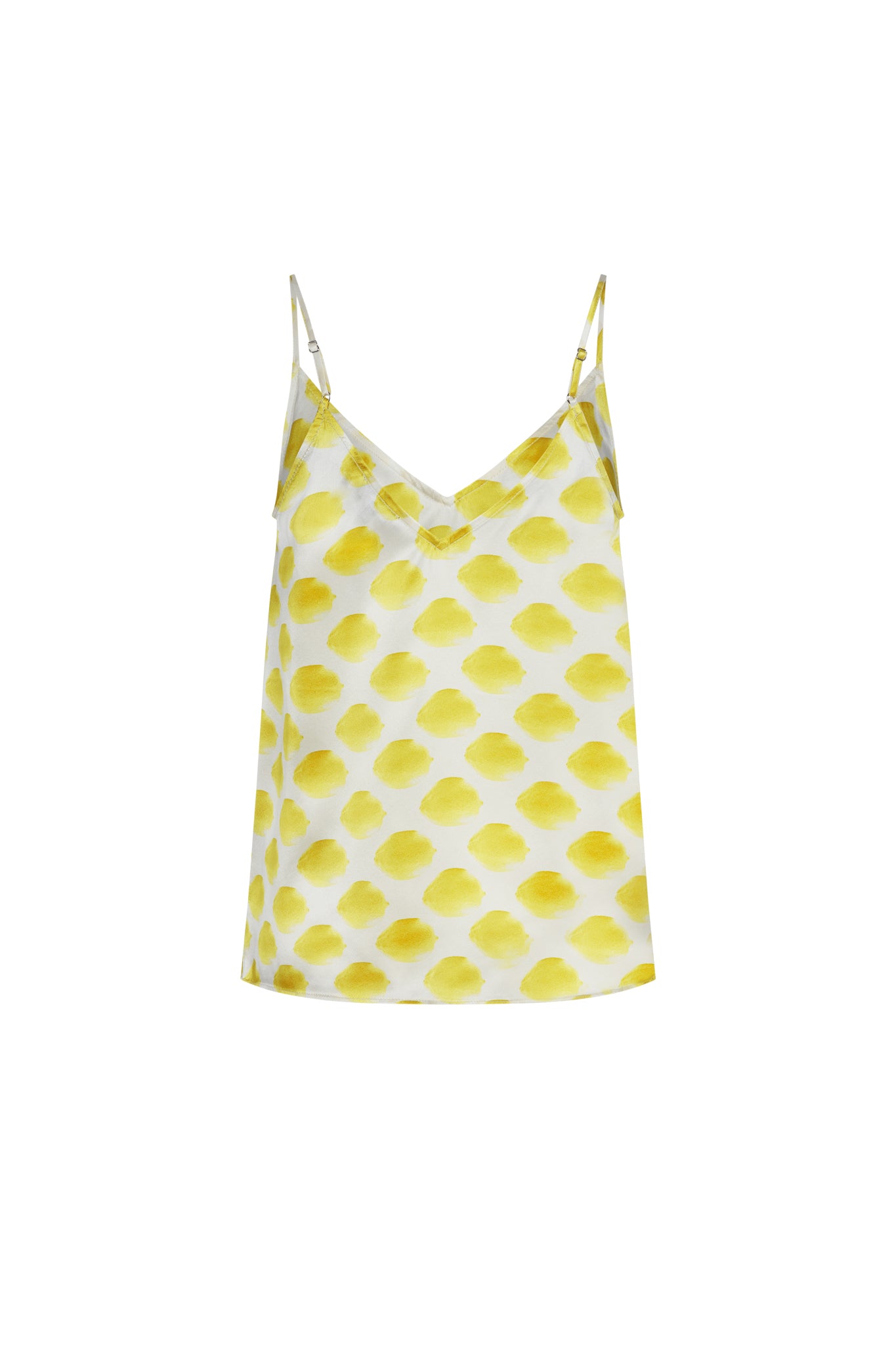Catherine Gee Franka Cami in the Limon White colorway features a delicate, lightweight fabric with a white base and a pattern of yellow lemon-like spots. The design includes thin adjustable straps and a V-neckline, giving it a casual yet elegant look. The bright and cheerful pattern makes it a standout piece for warm weather or layering under jackets and cardigans.
