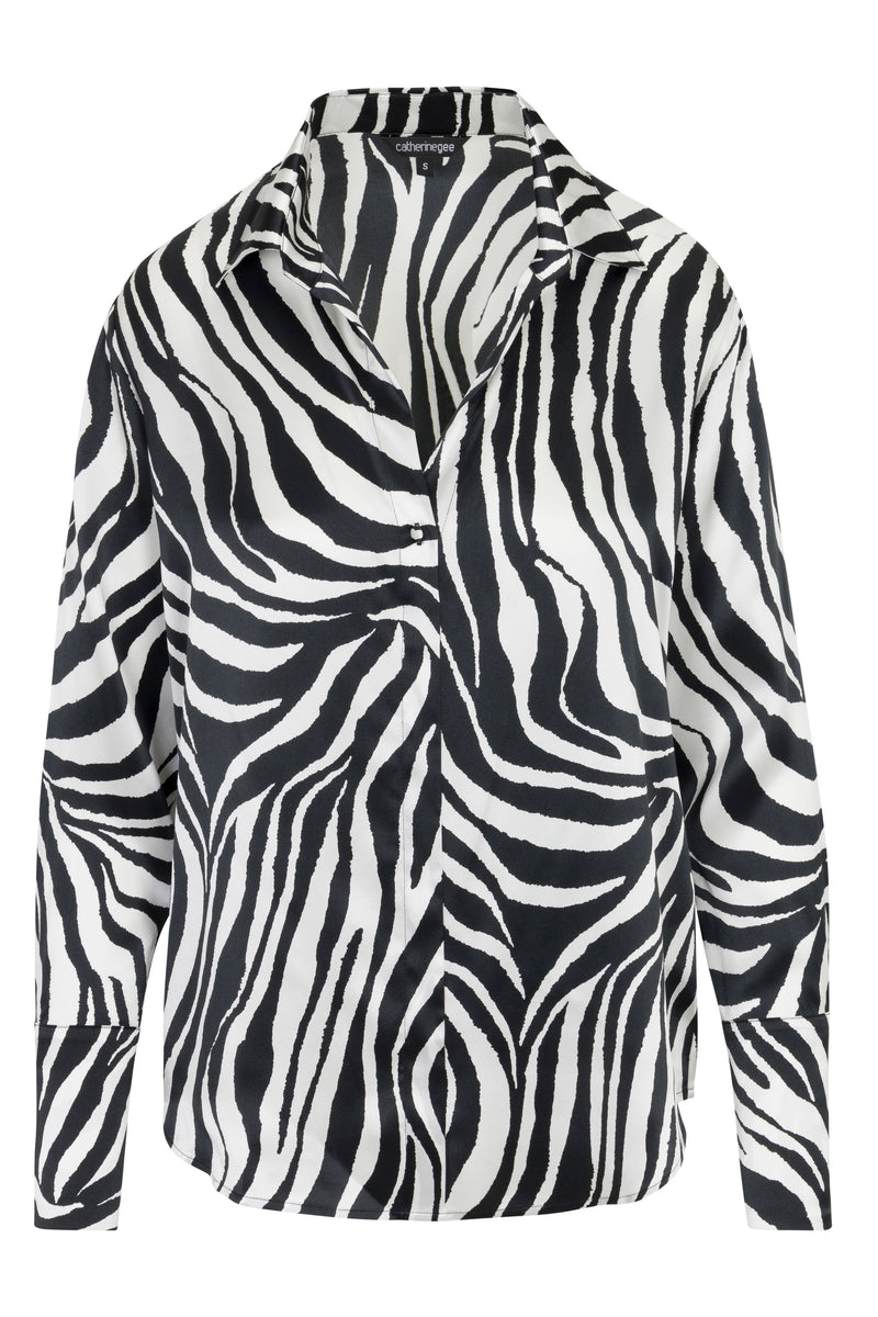 Catherine Gee Daria French Cuff Silk Zebra blouse features a striking black and white zebra print pattern, adding a bold touch to the classic design. Made from luxurious silk, it has a smooth texture and elegant drape. The blouse includes a classic collar, button-down front, and long sleeves with French cuffs, making it a sophisticated and stylish piece suitable for various occasions.