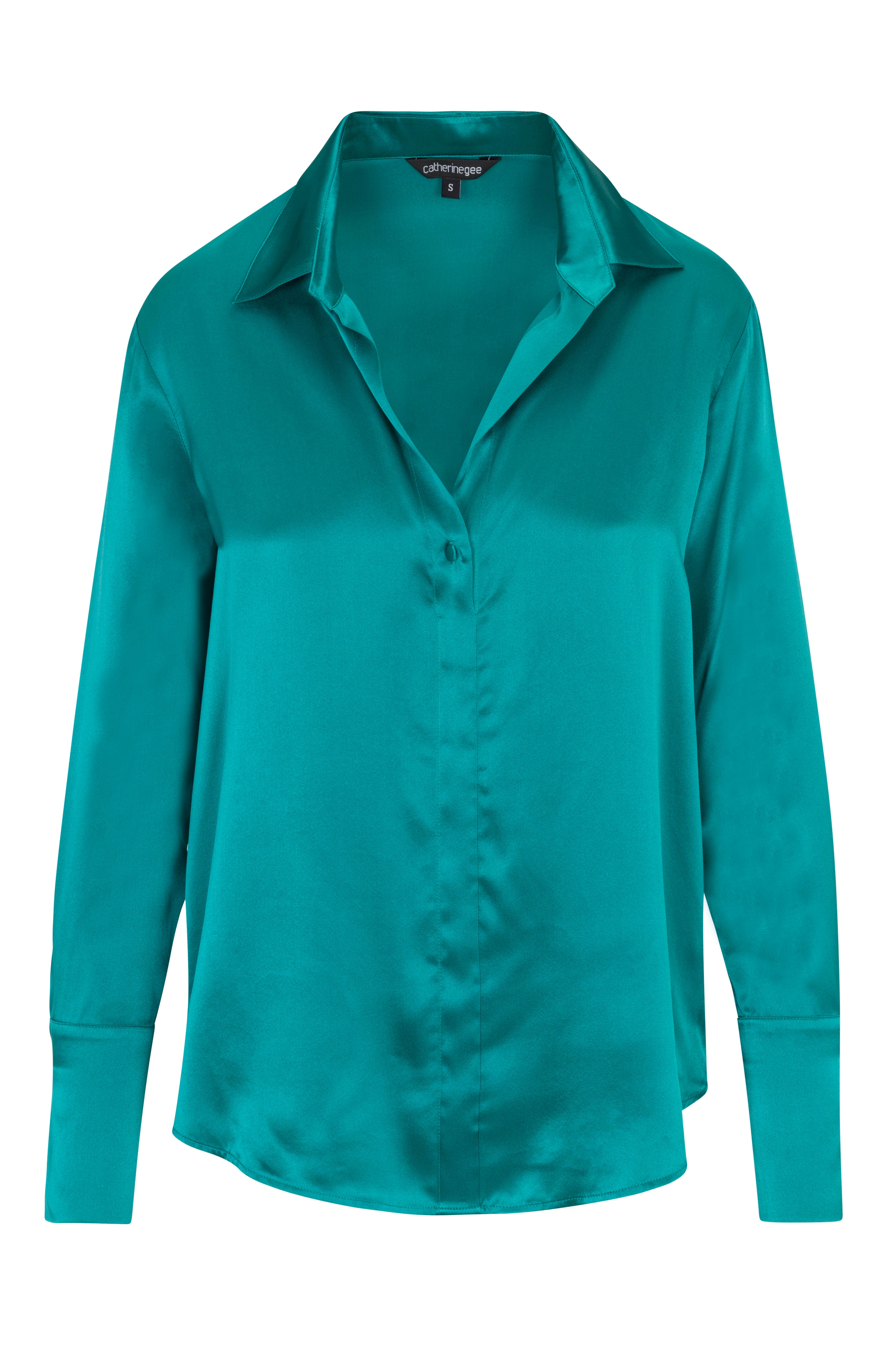 Catherine Gee Daria French Cuff Silk Teal blouse is made of luxurious silk fabric and features a vibrant teal color. It has a classic collar and a button-down front with French cuffs, adding a sophisticated touch to its design. The overall look is elegant and suitable for both professional and casual settings.