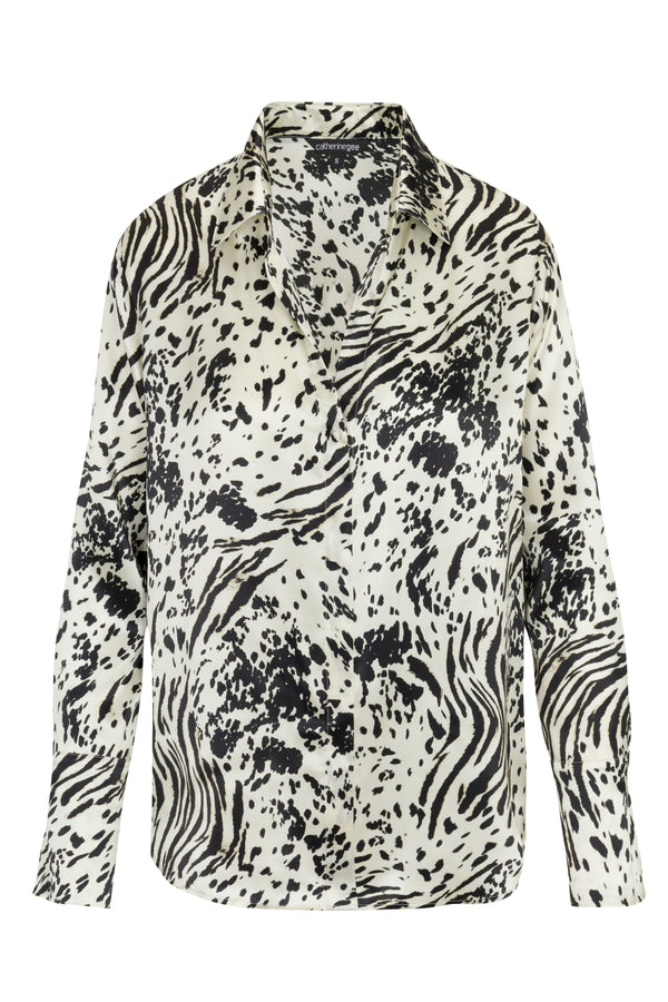 Catherine Gee Daria French Cuff Silk Zebra Graze blouse features a striking black and white zebra print pattern set against a plain white background. With its loose, flowing fit and elegant French cuffs, this garment beautifully combines a chic and wild style.