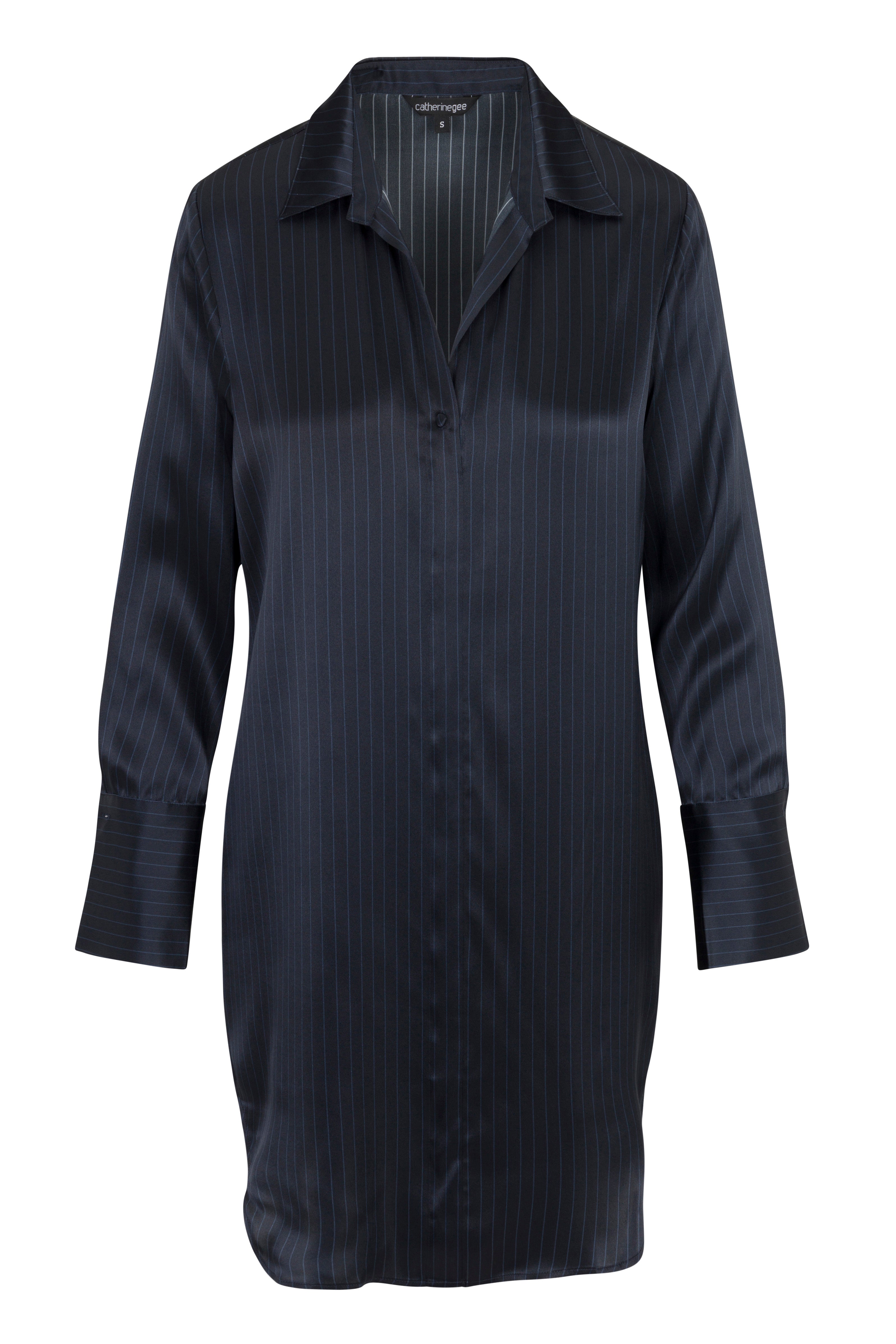 Catherine Gee Navy Pinstripe - Daria Dress features a collared neckline, long sleeves with wide cuffs, and a straight, relaxed fit. The fabric has a subtle sheen, and the pinstripes add a touch of sophistication to the overall design.