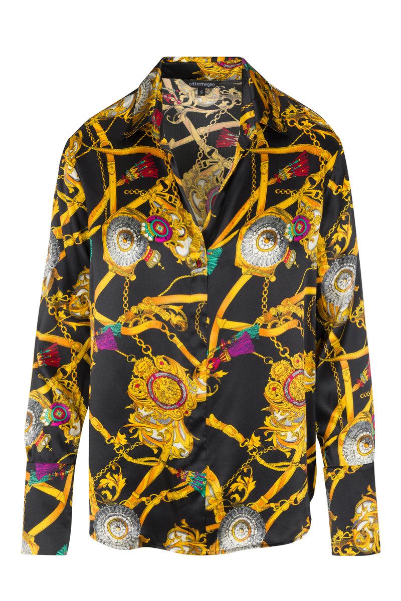 Catherine Gee Daria French Cuff Silk Versailles Blouse. This luxurious blouse features a vibrant and intricate pattern with gold chains, ornate medallions, and colorful accents on a black background. The design is opulent and eye-catching, making it a statement piece, has a classic collar and French cuffs, adding a touch of sophistication and elegance to the overall look.