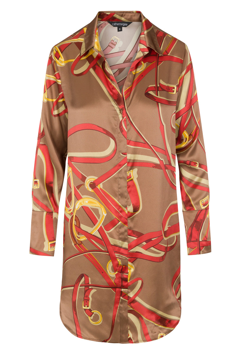 Catherine Gee Lexington Equestrian - Daria Dress features a brown base with an abstract pattern of red and yellow equestrian-themed elements, including belts and buckles. It has a collared neckline and long sleeves, with a button-down front. The fabric appears to be silky and smooth, giving it a luxurious look.