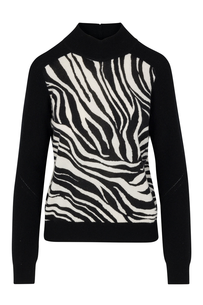 Catherine Gee Gwen Color Block Cashmere Zebra Sweater. This luxurious sweater features a striking zebra print pattern on the front, with bold black and white stripes creating a dramatic look. The sleeves, shoulders, and collar are solid black, providing a chic contrast. Made from high-quality cashmere, the sweater offers both comfort and style. The high neckline and fitted silhouette make it a fashionable and versatile piece for various occasions.