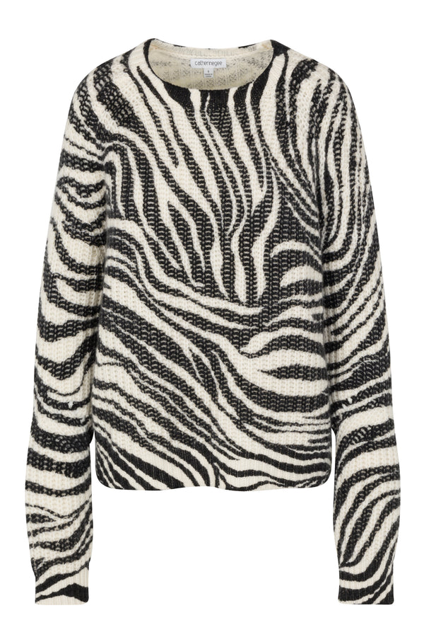 Catherine Gee Isabela Chunky Cashmere Zebra Sweater features a bold black and white zebra print pattern. Its design includes a chunky knit texture, long sleeves, and a round neckline. The striking zebra stripes create a visually appealing and fashionable look, making it a standout piece in any wardrobe. Additionally, the luxurious cashmere material enhances its appeal, providing both style and comfort.