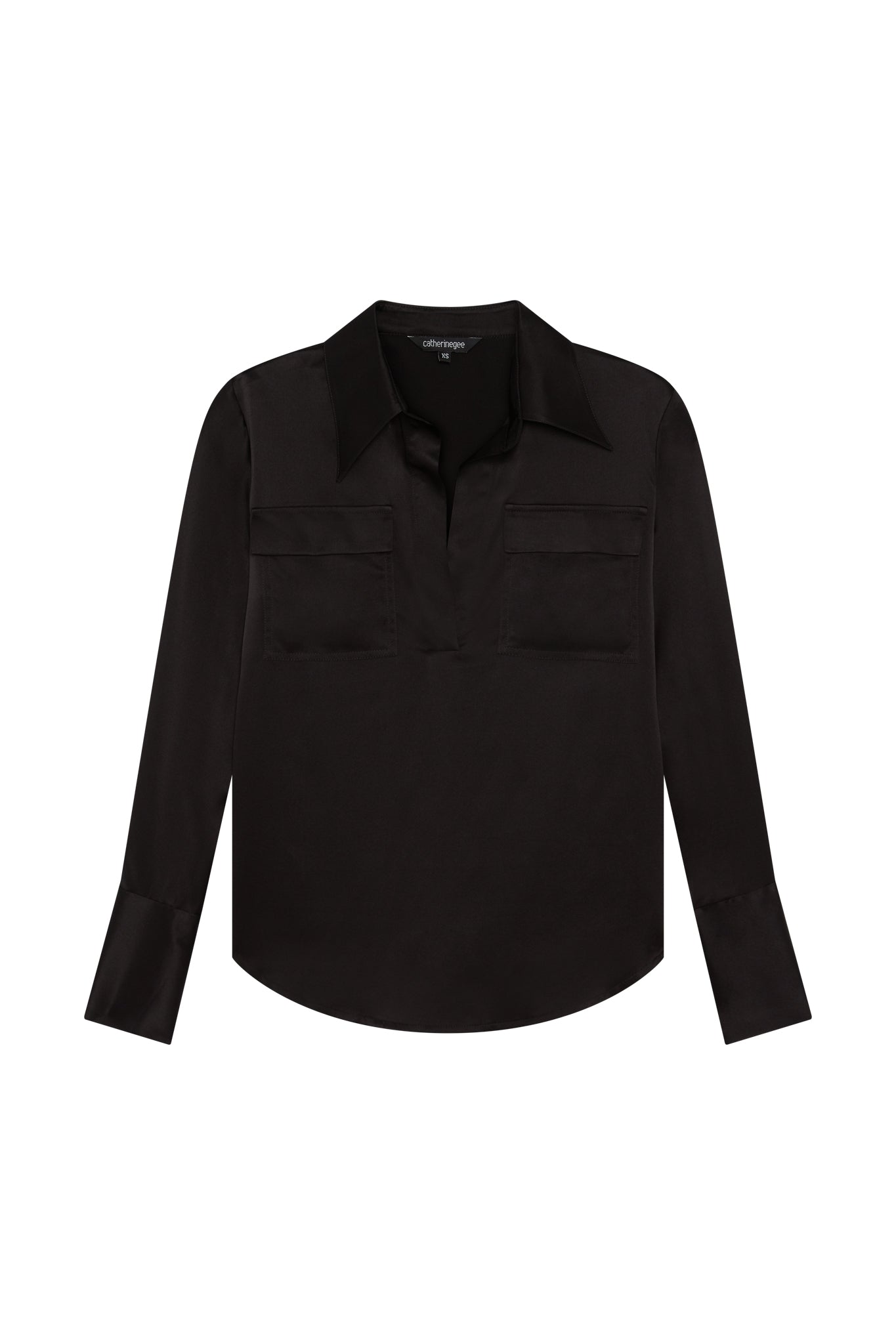 Catherine Gee Kaia Black Blouse. This elegant blouse features a deep black color with a sleek, smooth texture. It has a classic collar and a V-neckline, along with two chest pockets that add a touch of sophistication. The long sleeves are finished with wide cuffs, giving it a polished look. The blouse's design is both timeless and versatile, making it suitable for various occasions, from professional settings to casual outings.