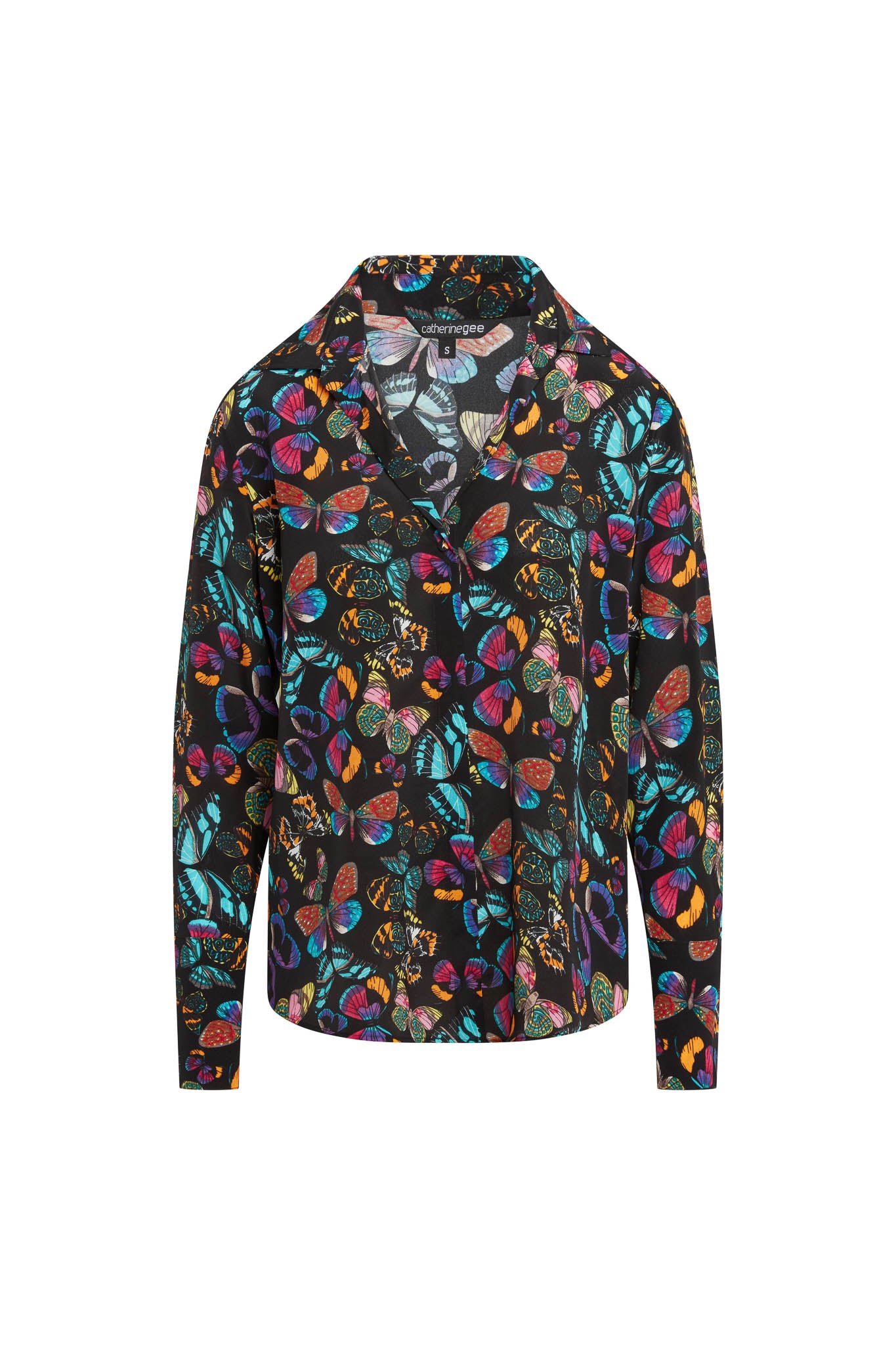 Catherine Gee Daria French Cuff Silk The Tracy blouse features a vibrant, multicolored butterfly print with various shades of blue, pink, orange, and green on a black background. The design includes a V-neckline with a collar and long sleeves with French cuffs. The silk material gives it a luxurious and elegant appearance, making it a standout piece for any wardrobe.