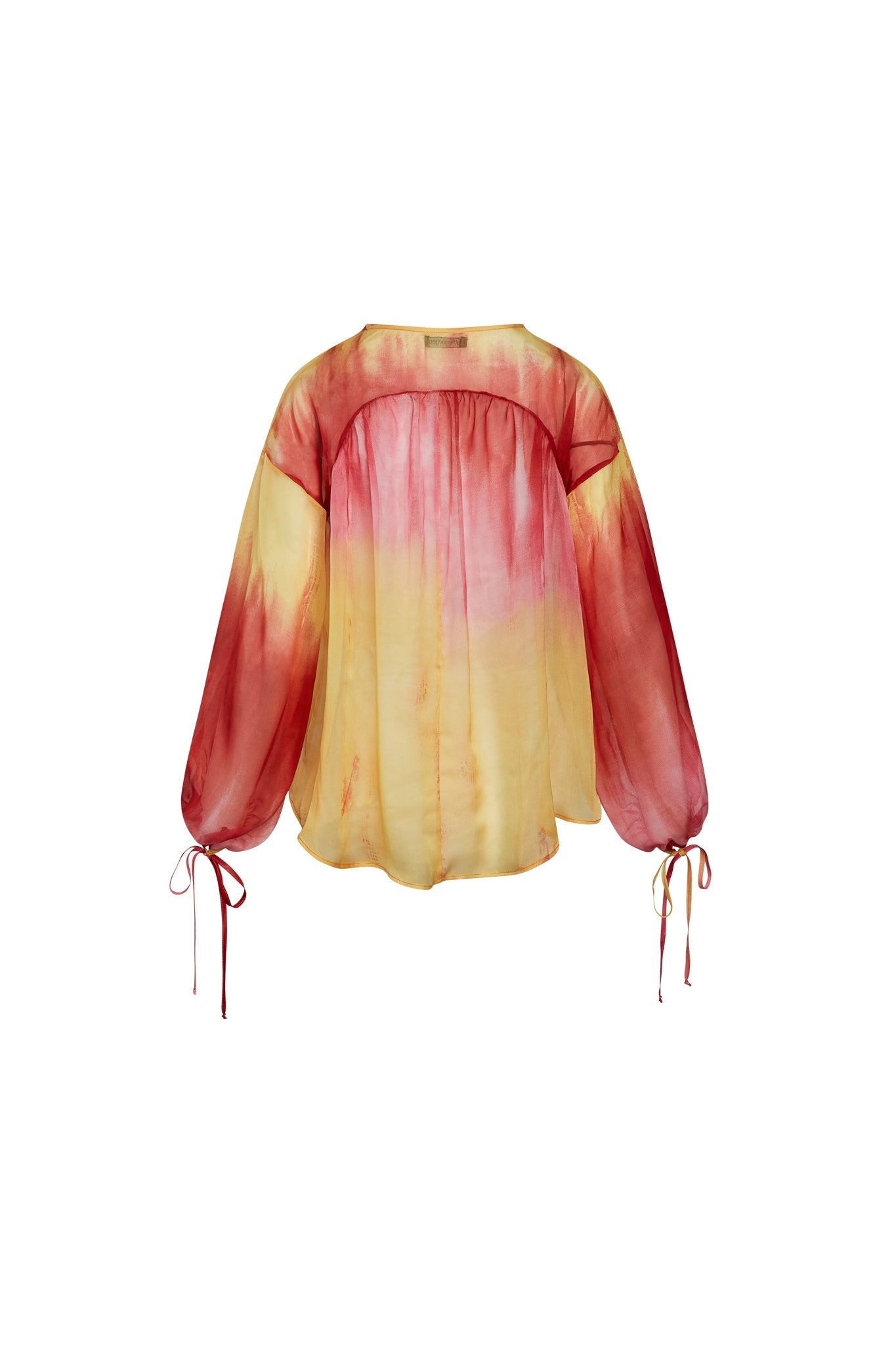 Back-view of a Catherine Gee Frances Santa Barbara Sunset blouse features a loose, flowing design with long sleeves that have tie details at the cuffs. The fabric has a gradient color pattern, transitioning from a deep red at the shoulders and sleeves to a warm yellow towards the bottom. The blend of colors resembles a sunset, giving the blouse a vibrant and eye-catching appearance.