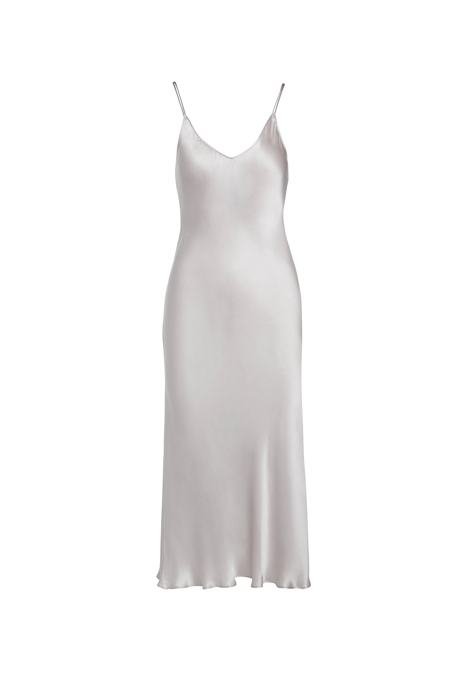 Catherine Gee Emma Silver Slip Dress. This elegant dress features a sleek, minimalist design with a smooth, satin-like finish, and has thin spaghetti straps, and a V-neckline, creating a sophisticated and timeless silhouette. The dress falls gracefully to a midi length, making it suitable for various occasions, from formal events to stylish evening outings. The silver color adds a touch of glamour and versatility to the garment.